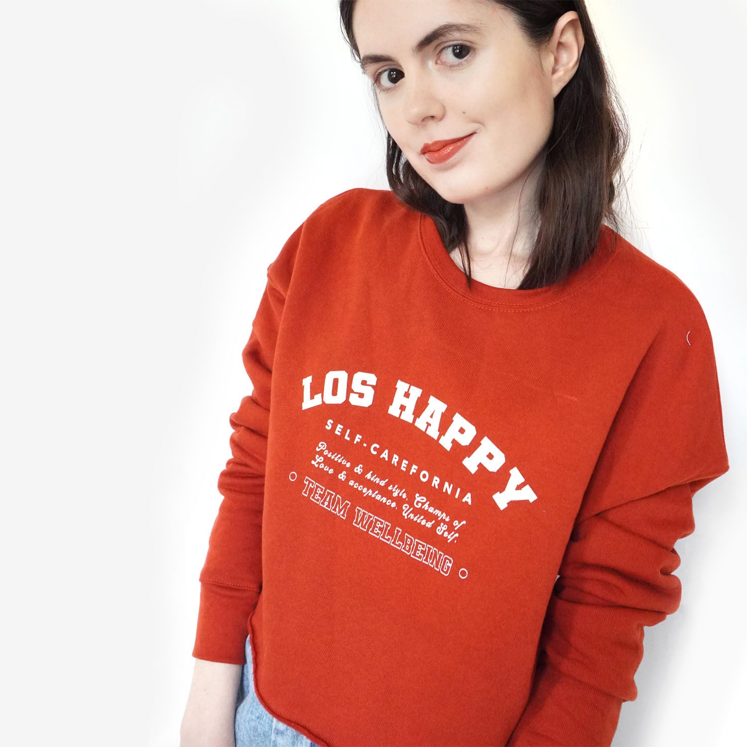 Side view of the cropped sweatshirt in red with slogan.